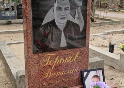 Вертикальный памятник из красного гранита с двойным гравированным портретом мужчины на черной вставке и золотой каллиграфической надписью