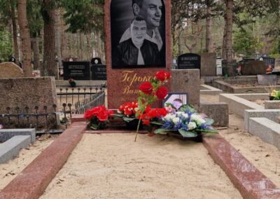 Памятник из красного гранита с двойным портретом и художественной гравировкой на кладбище в Эстонии